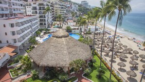Een resort met een zwembad, palmbomen en een strand voorzien van parasols.