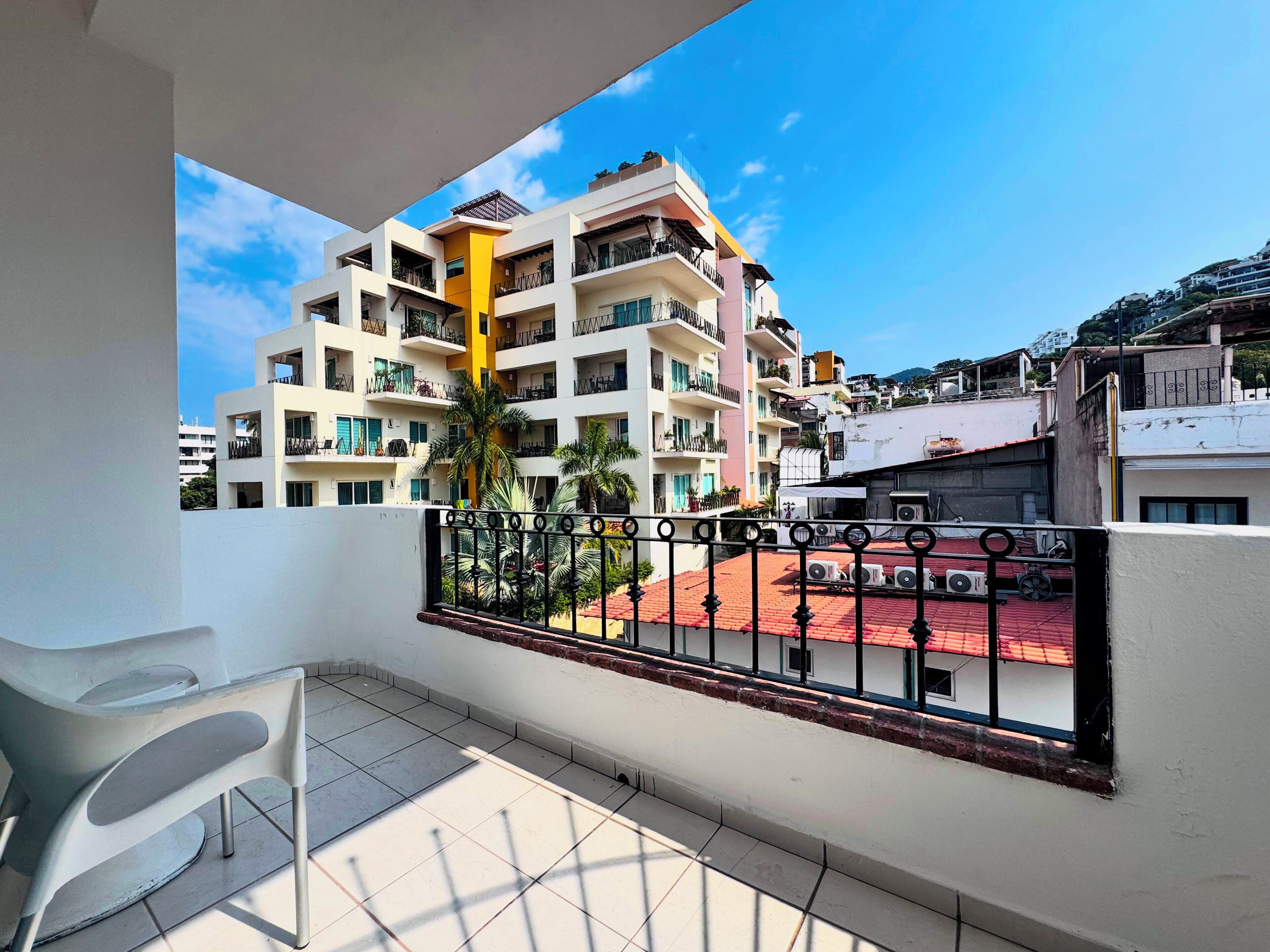 Un balcon donnant sur un immeuble à plusieurs étages, doté de balcons, de climatiseurs et d’un sol carrelé.