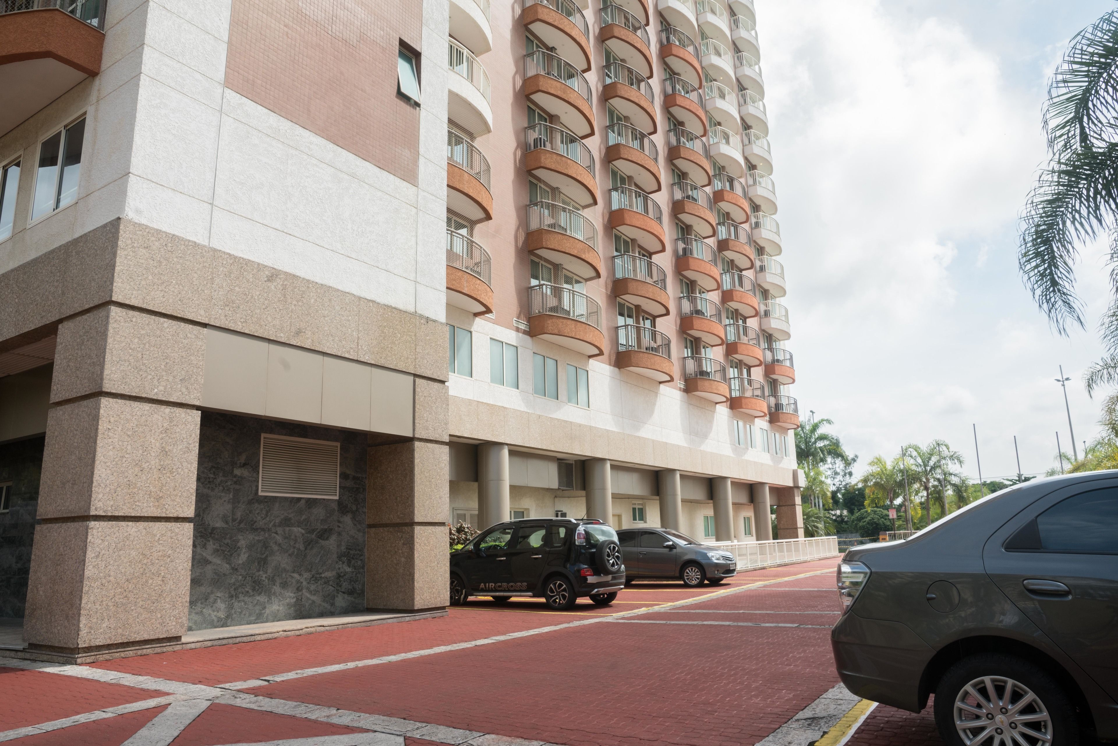 A multi-story building with a modern architectural design, featuring a mix of brick and stone facades, and a series of balconies on each floor.