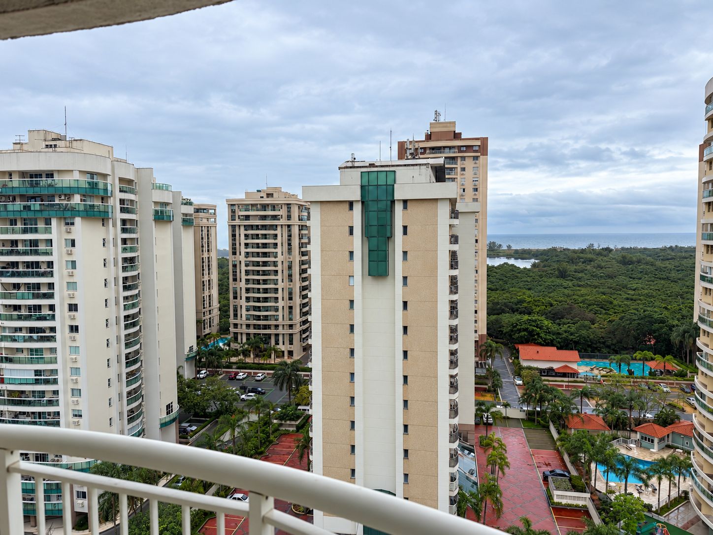 Un edificio residencial de gran altura con varios balcones, un complejo de piscinas y vistas a la costa.