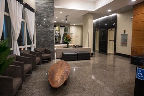 A lobby with seating, a reception desk, and an elevator. - Plaza Rio Residences - Barra First (Rio de Janeiro)