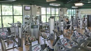 A gym with multiple treadmills, weight machines, and a television on the wall. - Plaza Rio Residences - Barra First (Rio de Janeiro)