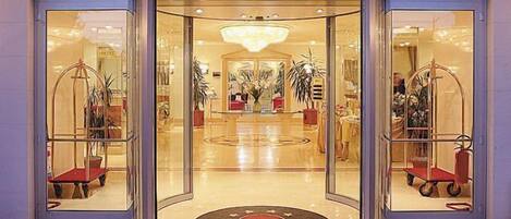 A hotel entrance with a revolving door, glass doors, and a central circular area with a logo.