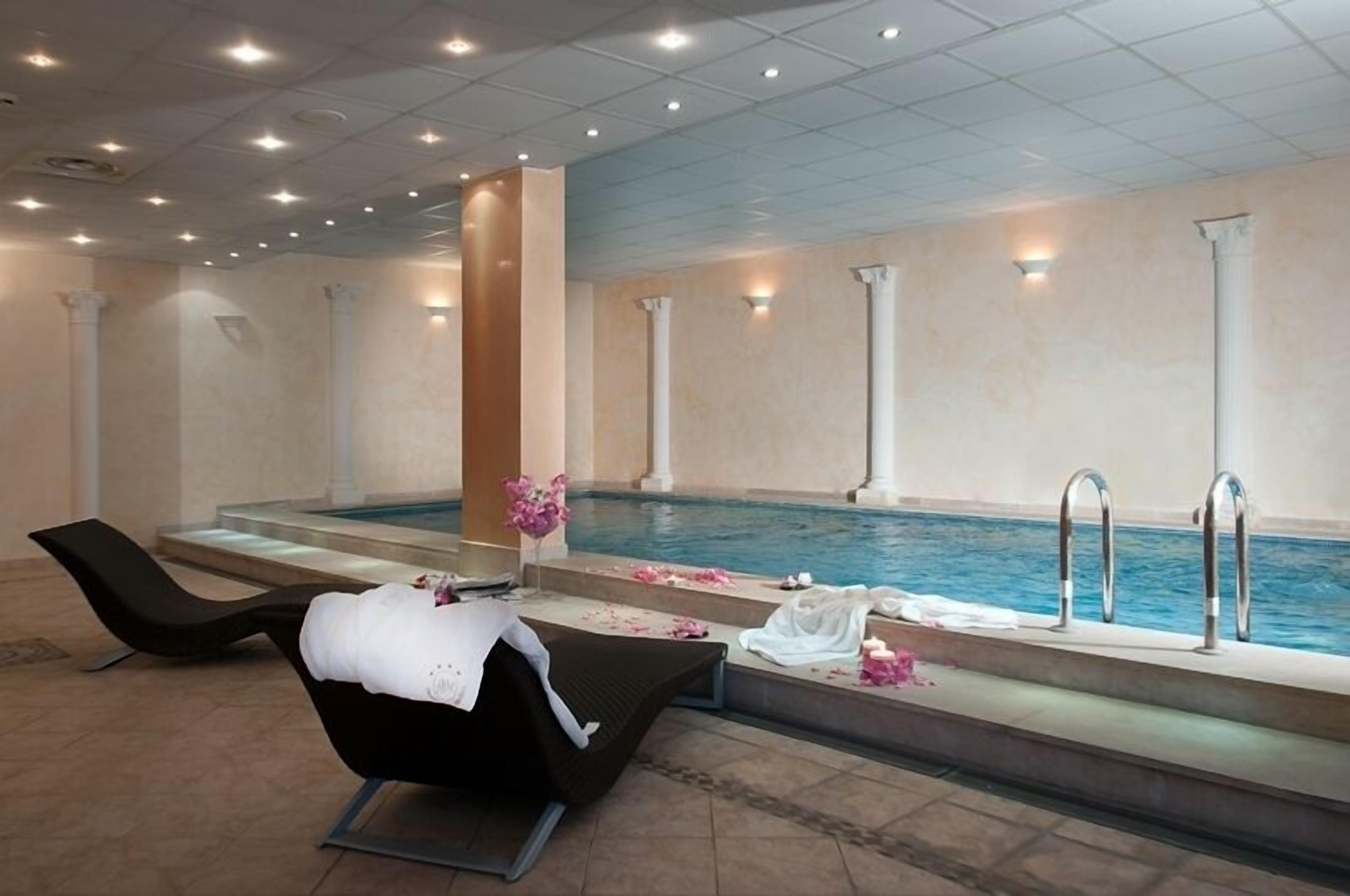 Un área de spa con piscina, sillones de descanso y una pequeña mesa con un florero.