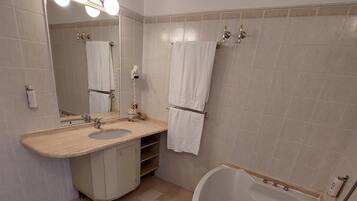 Une salle de bain avec une baignoire, un lavabo, un miroir et un porte-serviettes.