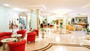 Eine großzügige Lobby mit roter Sitzmöbeln, einem Empfangsbereich und einem Essbereich mit Tischen.