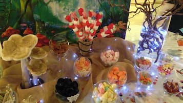Un tavolo con diversi cibi e decorazioni, sullo sfondo di un dipinto a tema foresta.