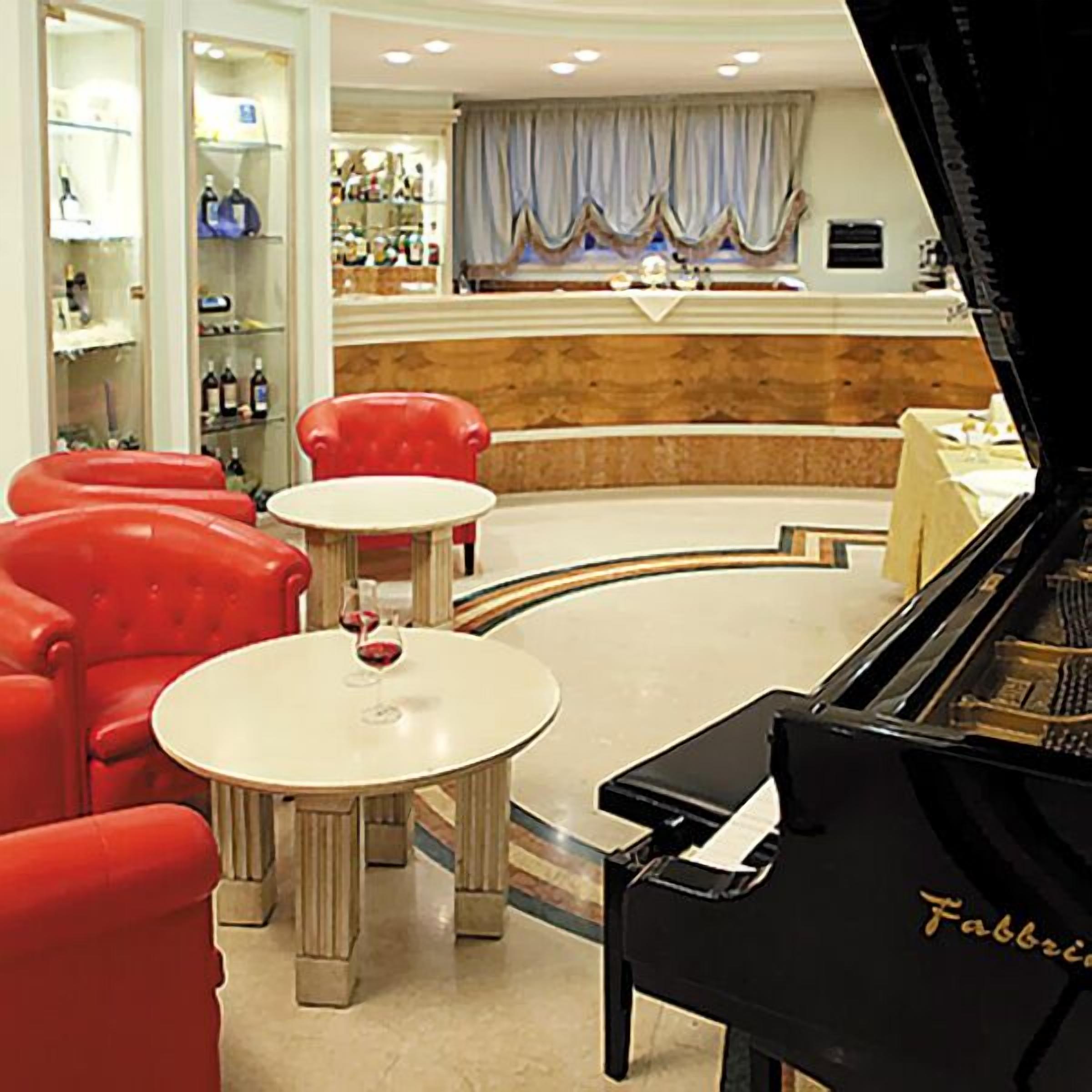 Un piano de cola en una sala de estar con sillas rojas y una pequeña mesa.