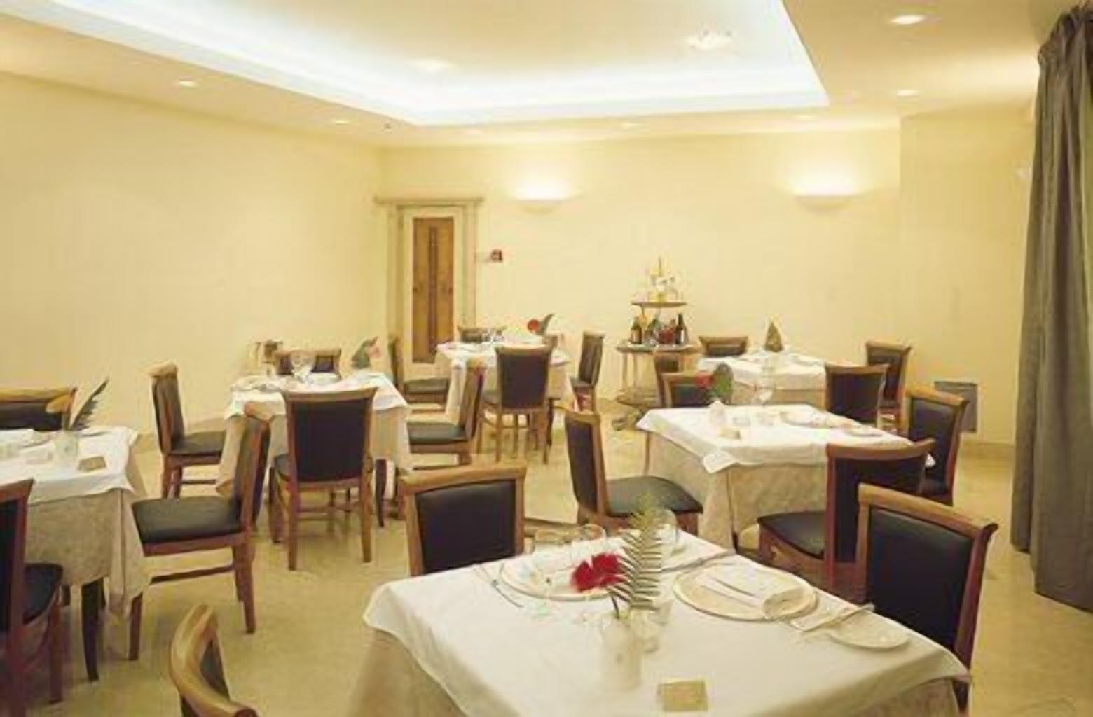 A hotel dining area with multiple tables and chairs, arranged in a spacious layout.