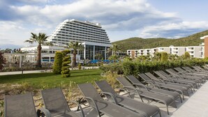Un hôtel doté d’un espace piscine avec des chaises longues et d’un grand bâtiment à l’architecture moderne.