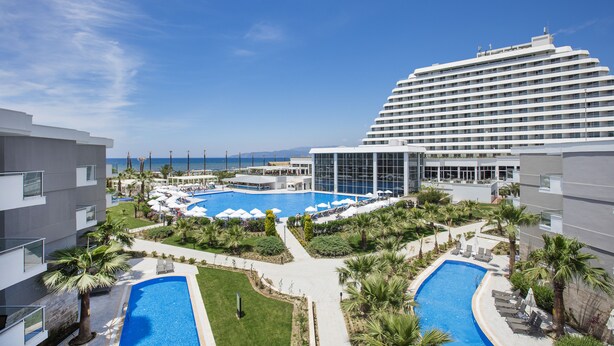 Un hôtel doté d’une grande piscine, de nombreux chaises longues et offrant une vue sur la mer.