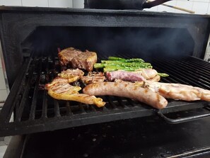 A grill with various meats and vegetables being cooked.