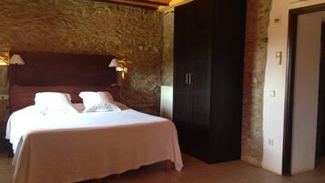 A bedroom with a bed, a wardrobe, and a stone wall.