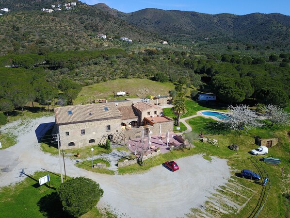 A large stone building with a tiled roof, surrounded by a well-maintained lawn and a swimming pool.