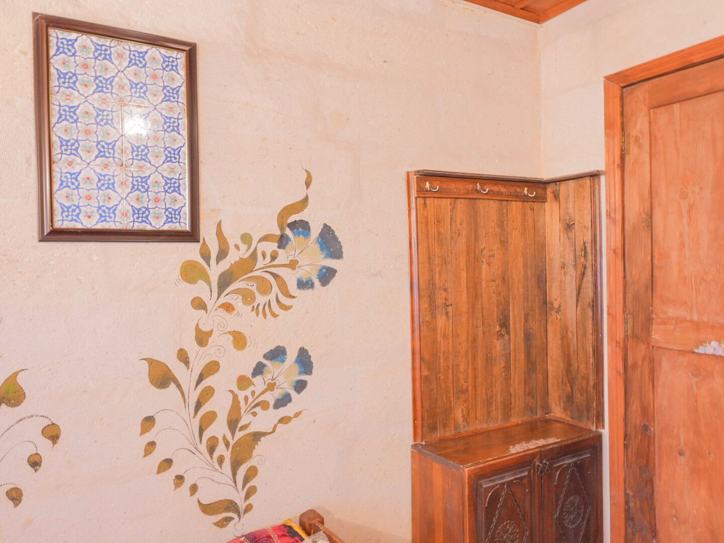 A room with a wooden cabinet, a door, and a framed tile with a geometric pattern on the wall.
