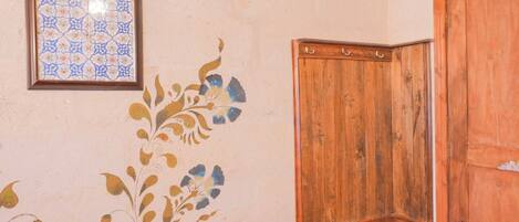 A room with a wooden cabinet, a door, and a framed tile with a geometric pattern on the wall.