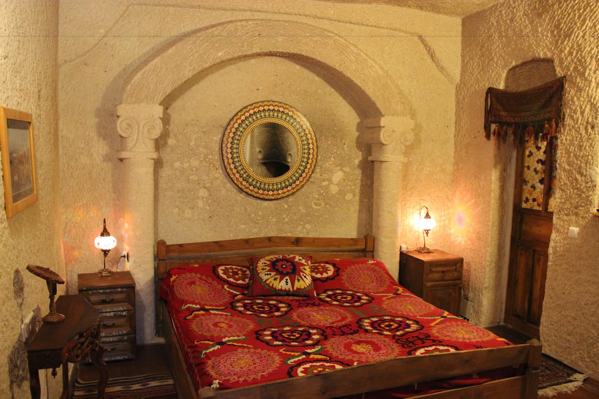 Ein traditionell eingerichteter Raum mit einem hölzernen Bett, einem Spiegel und zwei Nachttischlampen.