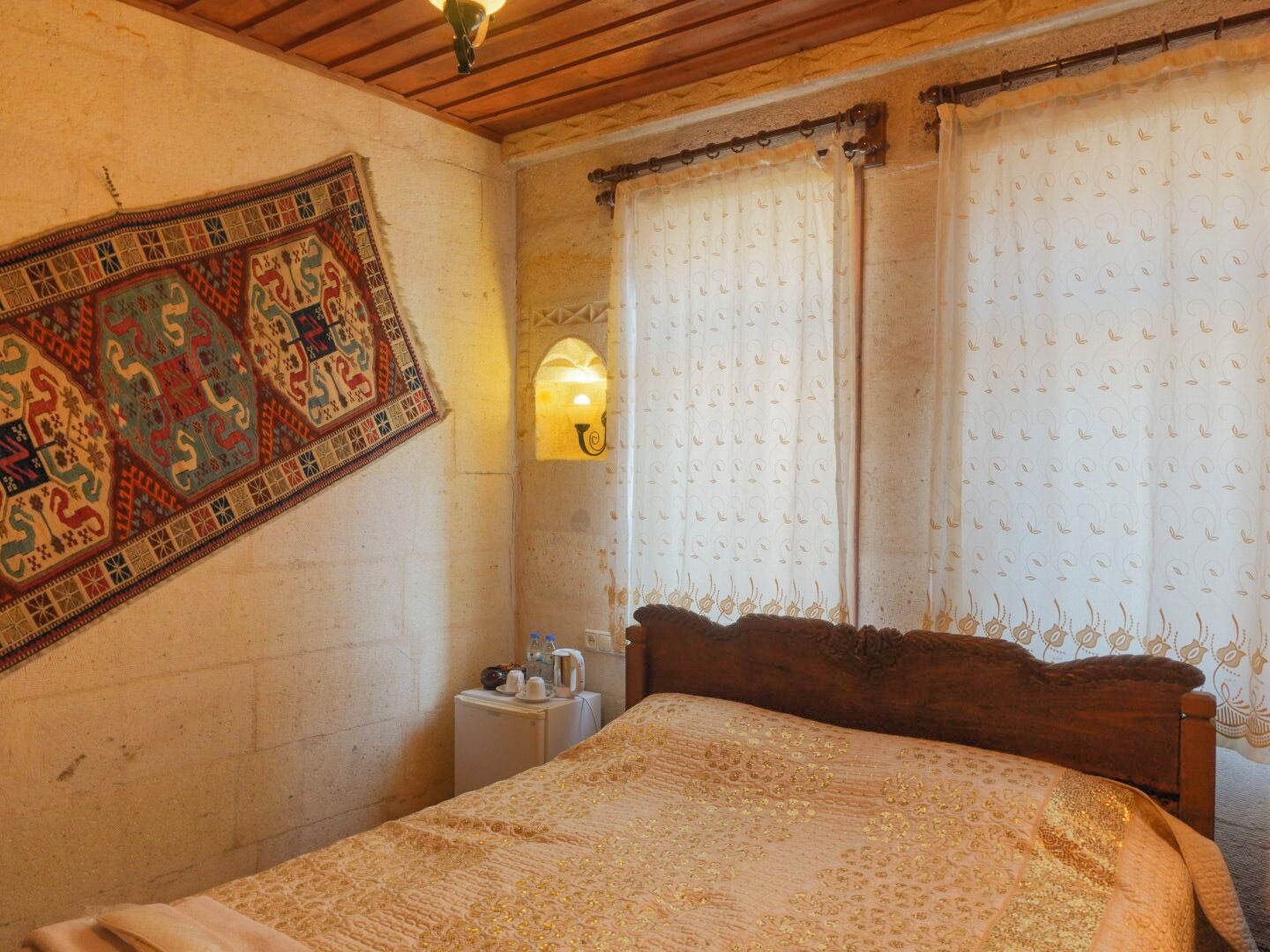 A traditional room with a wooden bed, a patterned rug, and a wall-mounted light fixture.