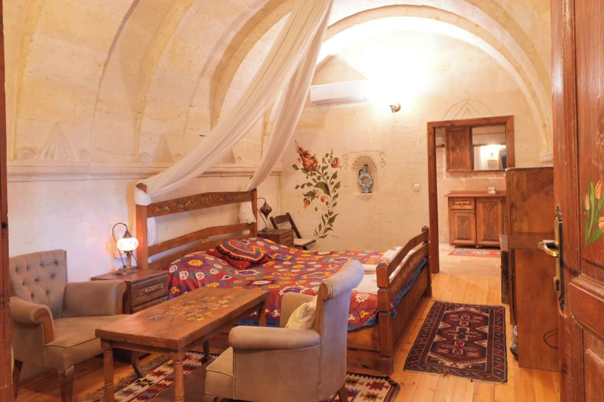 Ein Zimmer mit einem Bett, einem Sessel, einem Tisch und einem Holzschrank.