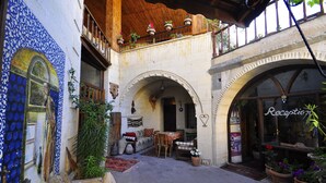 Ein Innenhof mit Rezeption, Essbereich und einem Balkon mit Blumentöpfen.