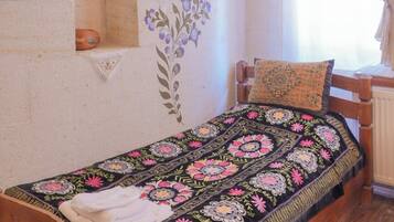 A bedroom with a wooden bed, a decorative wall, a light fixture, and a window with curtains.