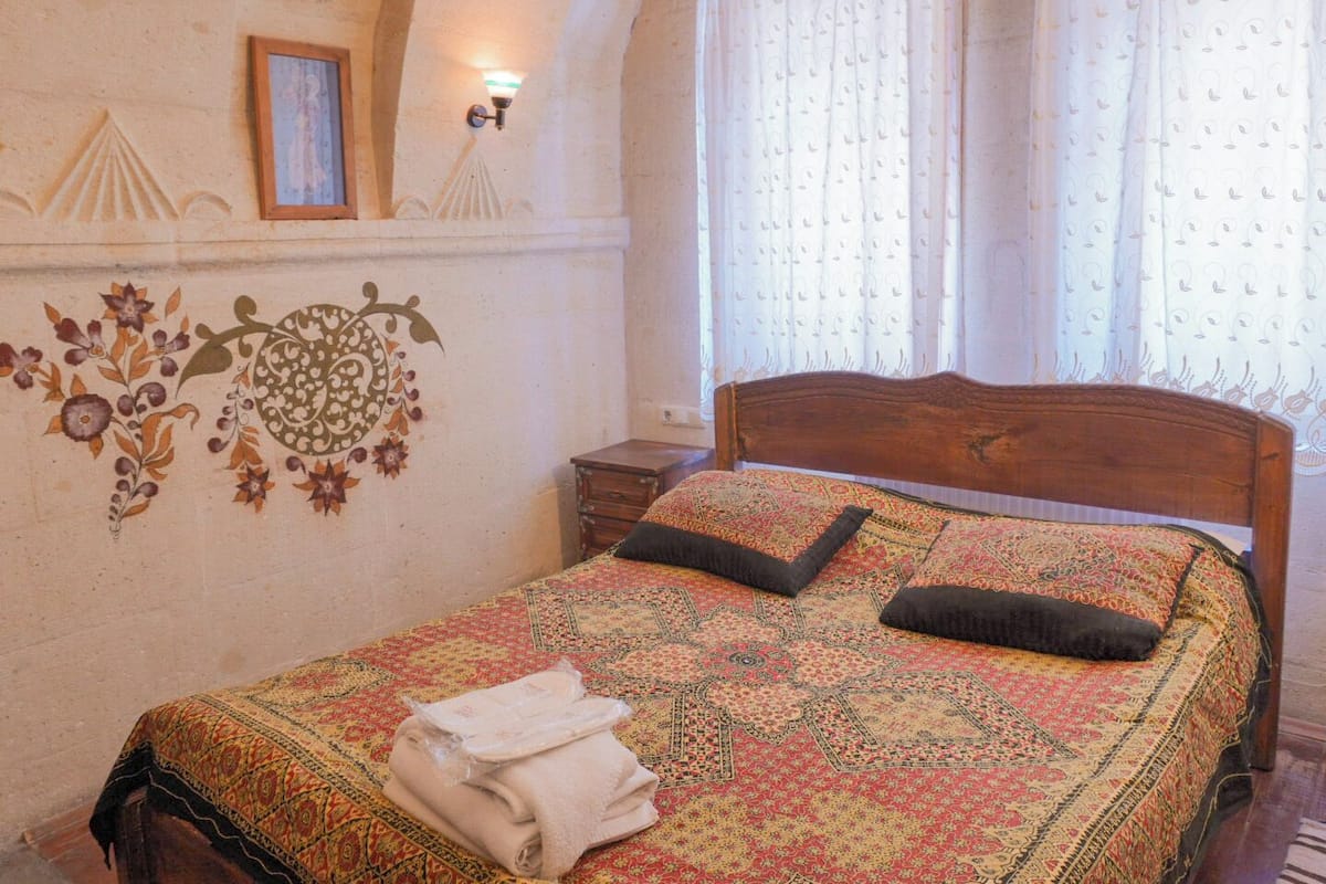 Ein Schlafzimmer mit einem hölzernen Bett, einem gemusterten Bettbezug und einer Wandverzierung.