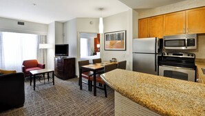 A compact kitchen with granite countertops, wooden cabinets, a refrigerator, microwave, and stove. - Residence Inn by Marriott Gulfport-Biloxi Airport (Gulfport)