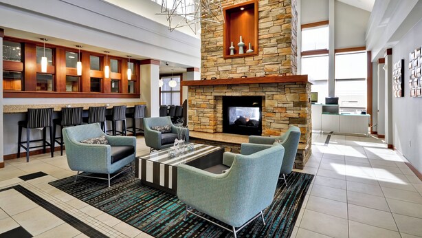 A spacious lobby with a stone fireplace, comfortable seating, a bar area, and large windows allowing natural light. - Residence Inn by Marriott Gulfport-Biloxi Airport (Gulfport)