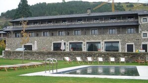 Un bâtiment en pierre doté d’une piscine, d’un espace extérieur aménagé et offrant une vue sur une colline boisée.