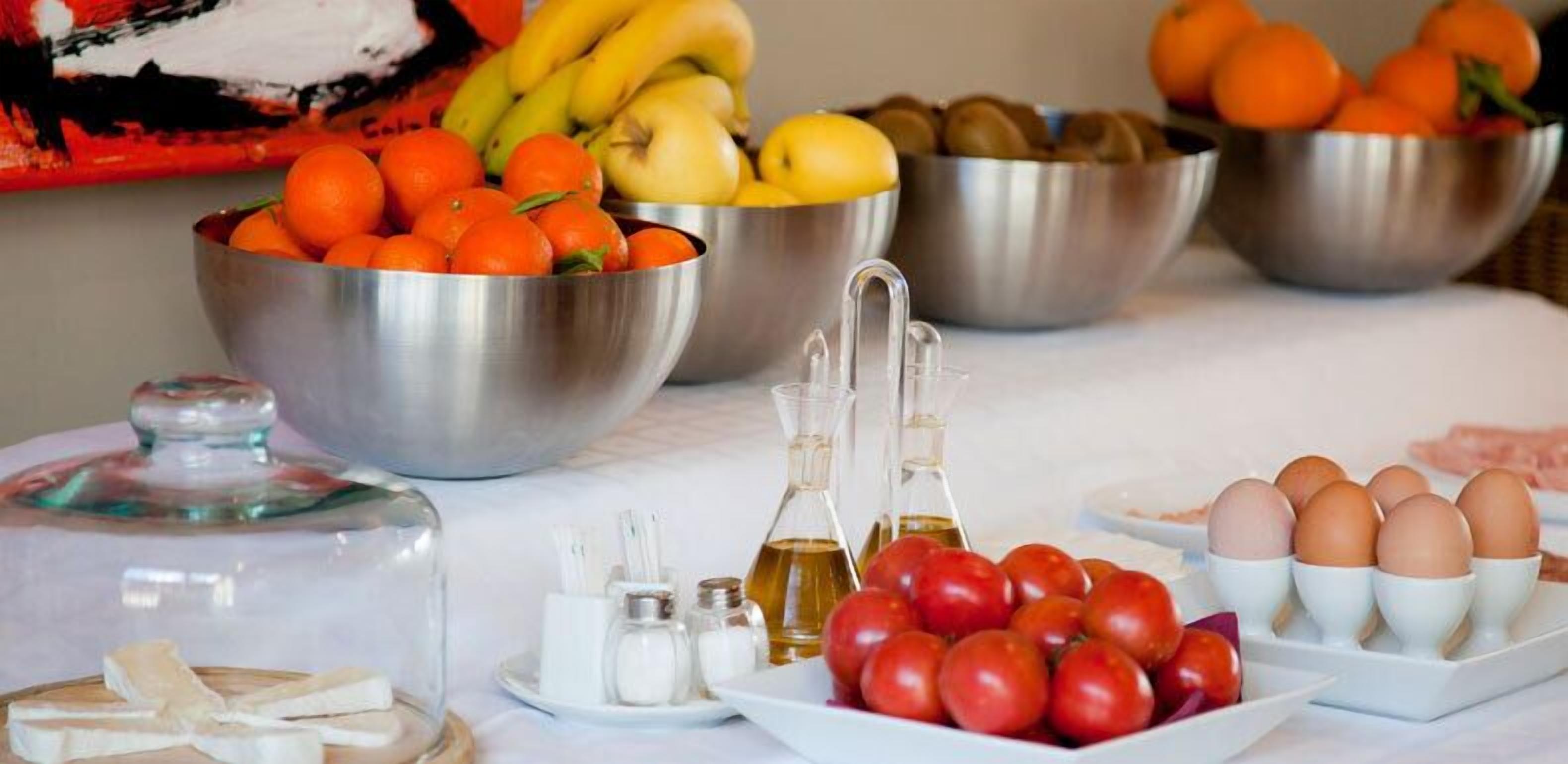 A table with various food items including oranges, bananas, apples, and eggs.