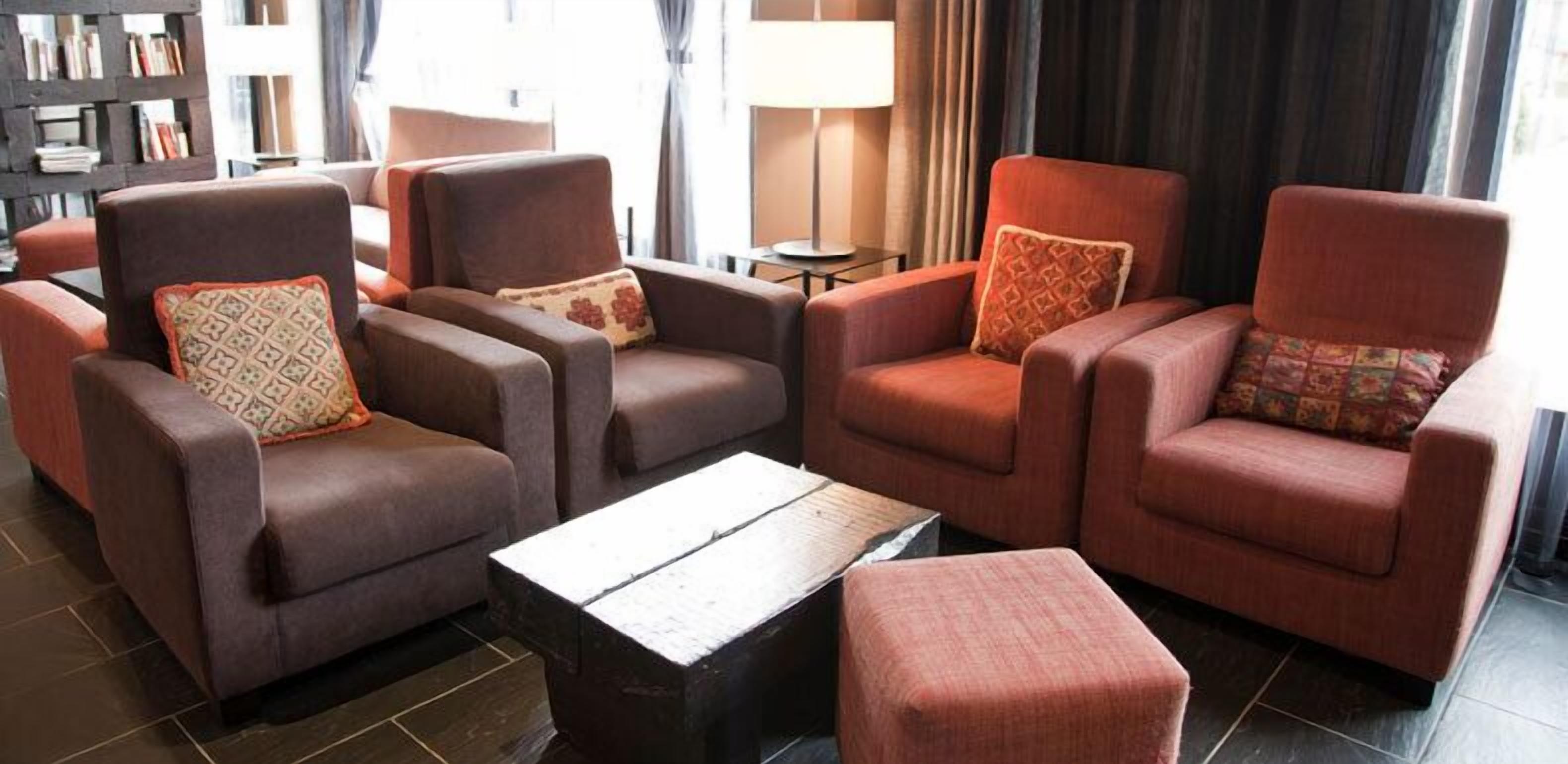 A living room with three armchairs, a coffee table, and a bookshelf in the background.