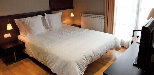 A neatly made bed with white linens in a hotel room.
