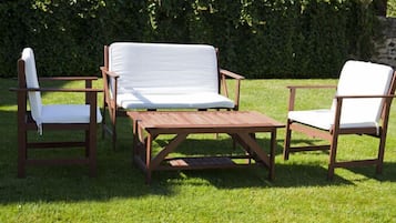 Un área de estar exterior de madera con dos sillas y una mesa.