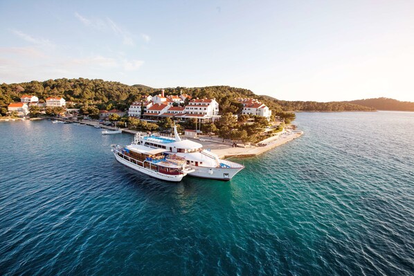 A large yacht docked at a marina with a coastal town in the background.