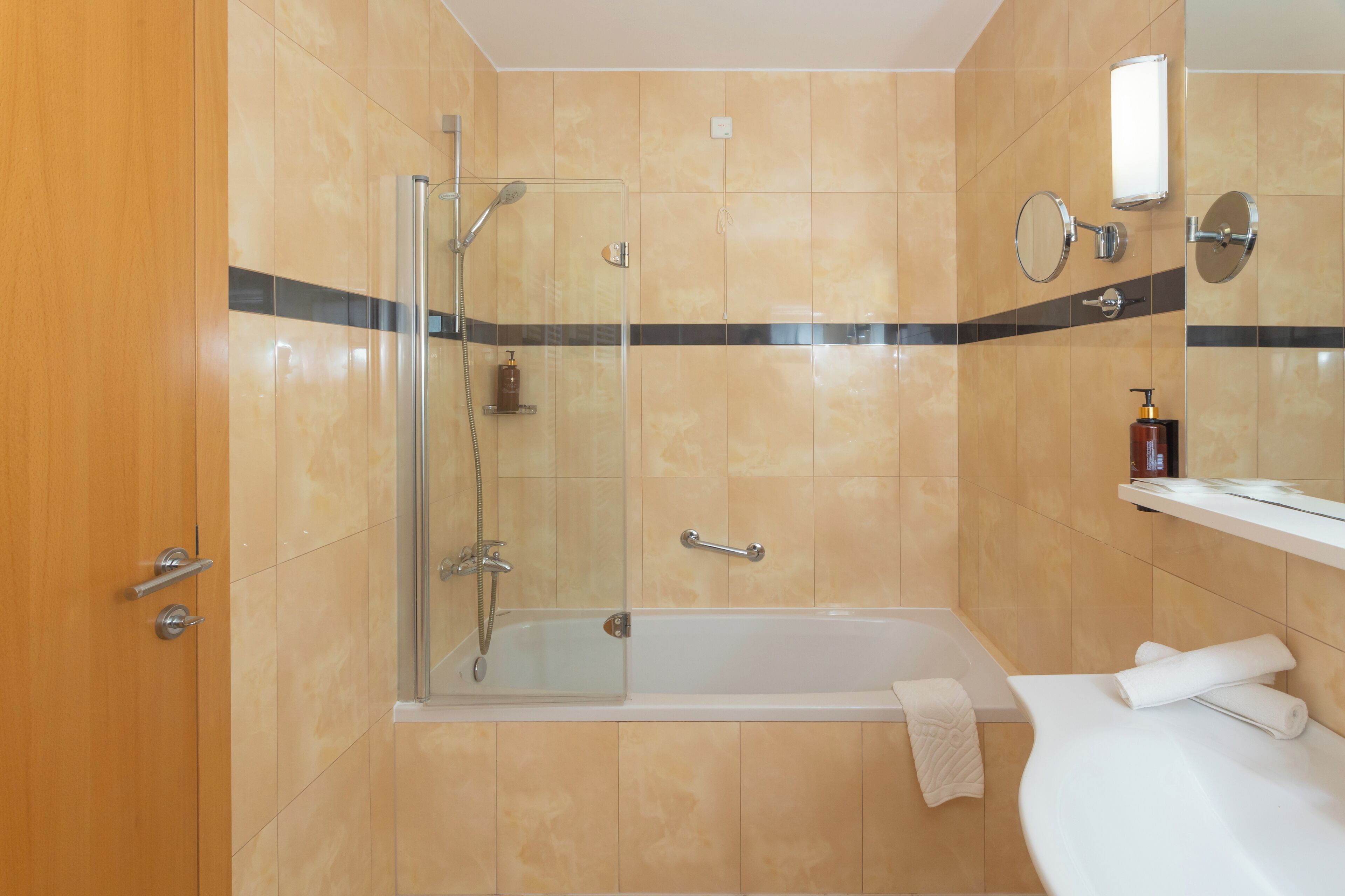 A modern bathroom with a glass-enclosed shower, a bathtub, and a vanity with a mirror and towel.