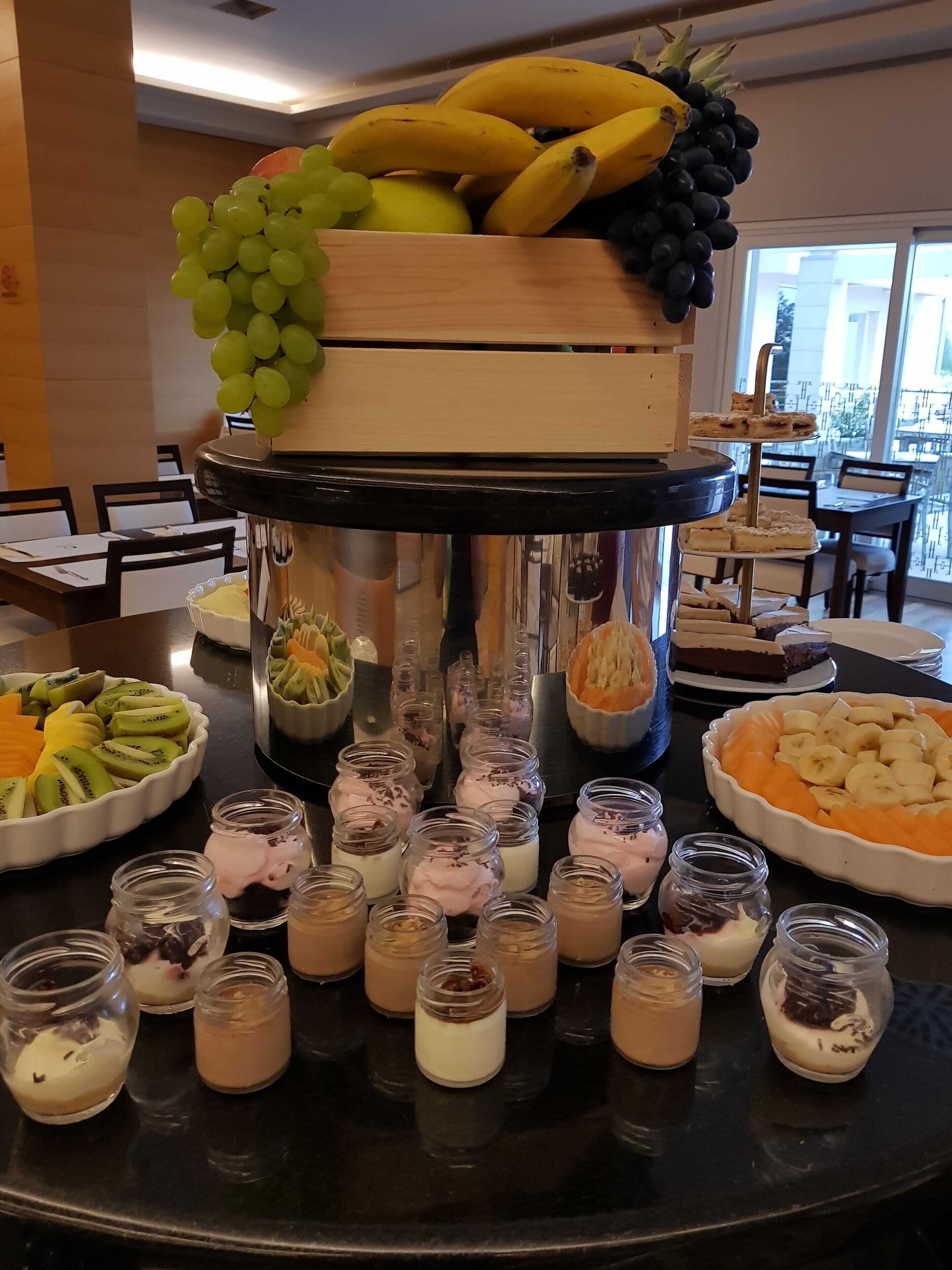 Une table de buffet proposant une variété d’aliments, notamment des fruits, des desserts et des boissons.