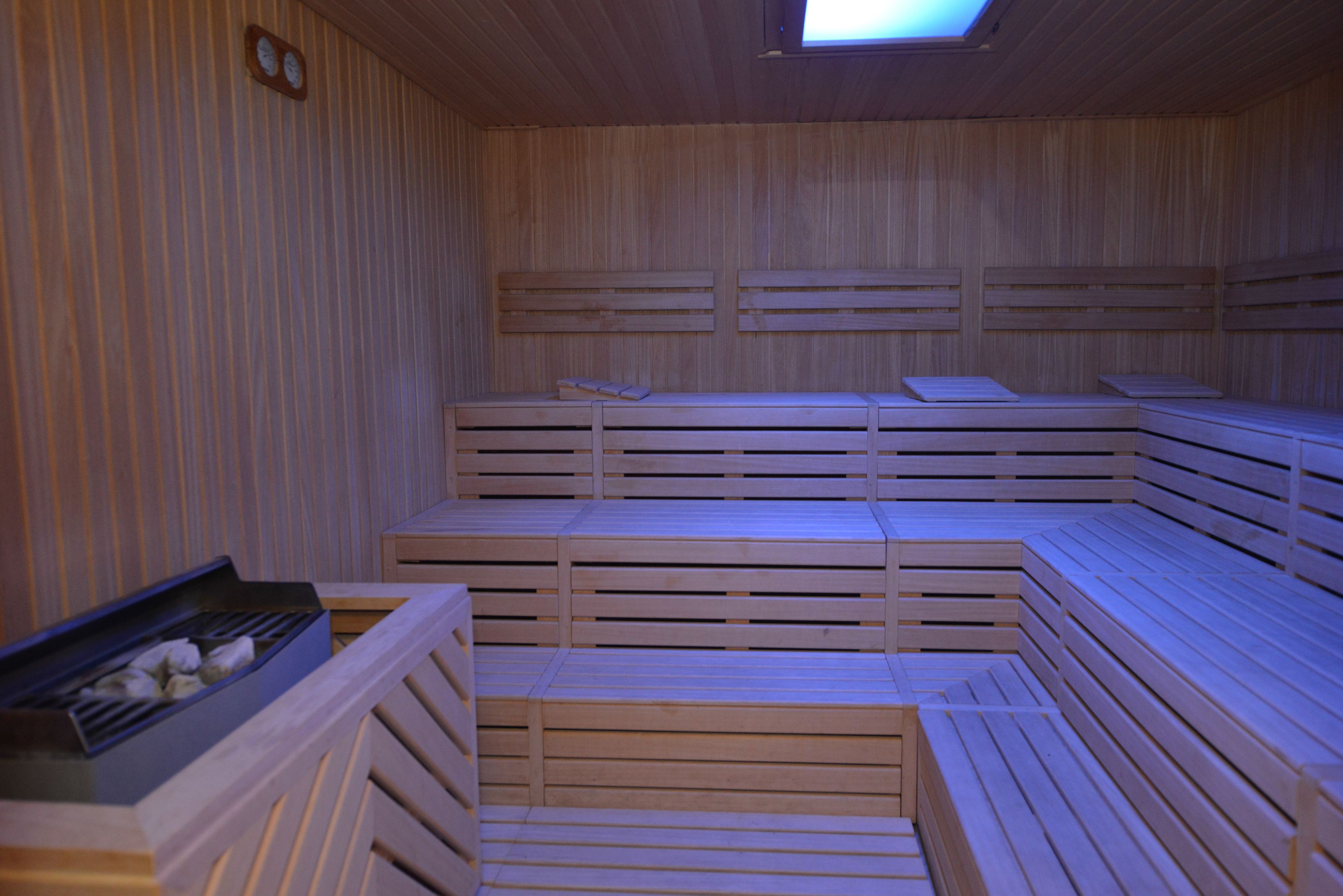 A sauna with wooden benches and a bench with a tray of stones.