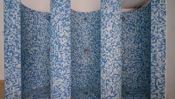Área de chuveiro revestida com azulejos e um padrão de mosaico.