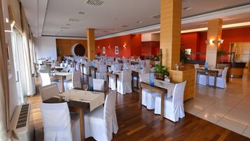A spacious dining area with multiple tables and chairs, large pillars, and a red accent wall.