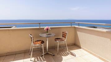 A balcony with two chairs and a table, overlooking a body of water.
