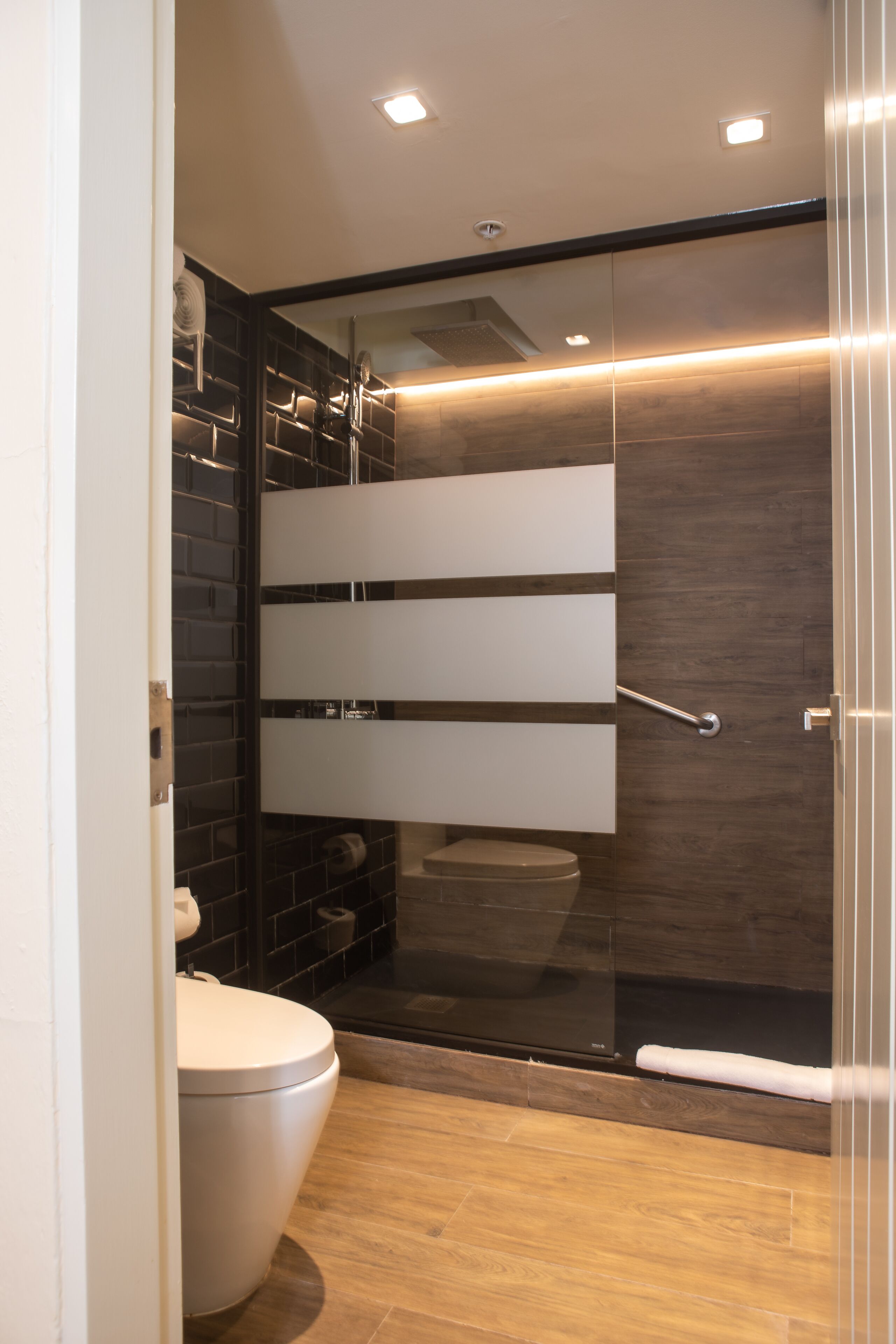 Un baño moderno con cabina de ducha de vidrio, inodoro y tocador con espejo.