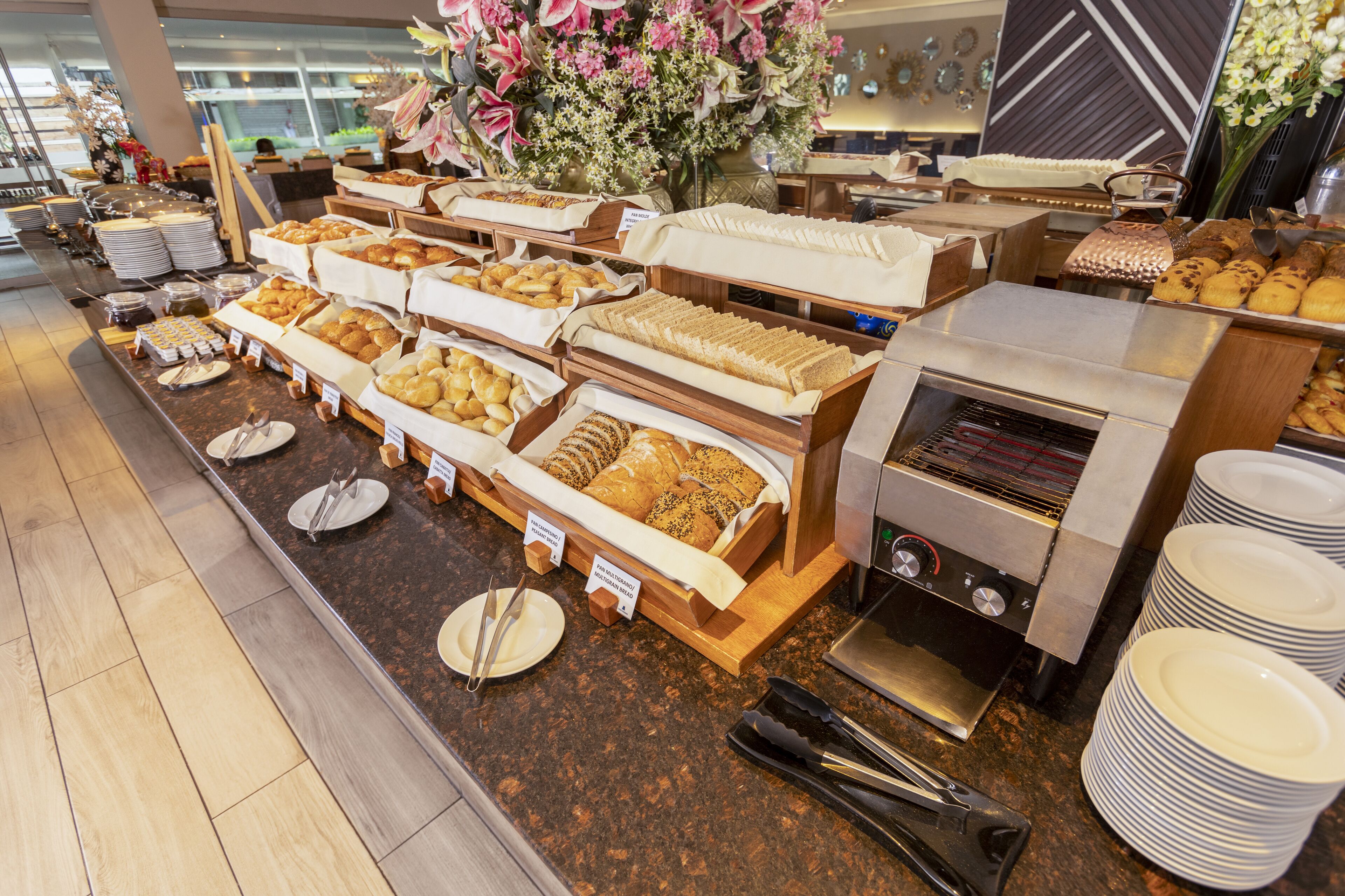 Ein Buffet mit verschiedenen Speisen, einer Kaffeemaschine und einer Blumenkomposition.