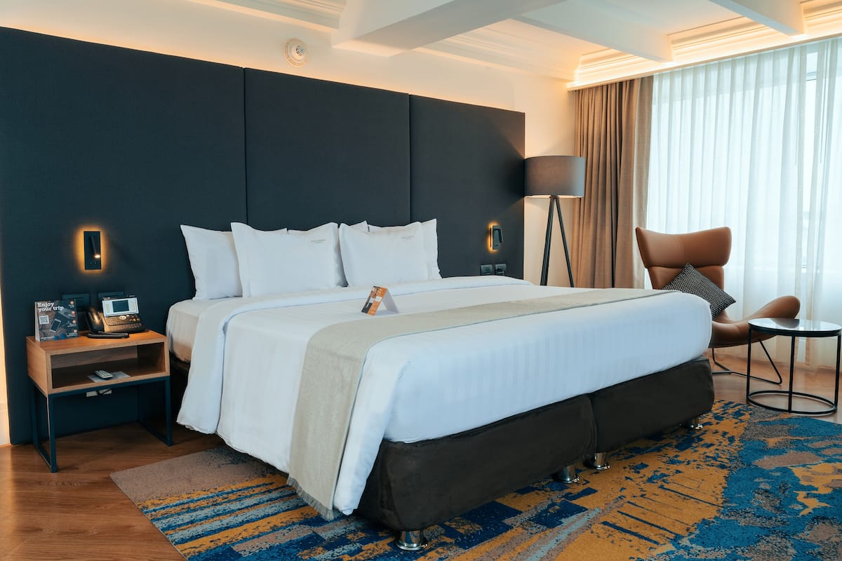 Une chambre d’hôtel moderne, dotée d’un grand lit, de tables de chevet, d’un bureau et d’une chaise.