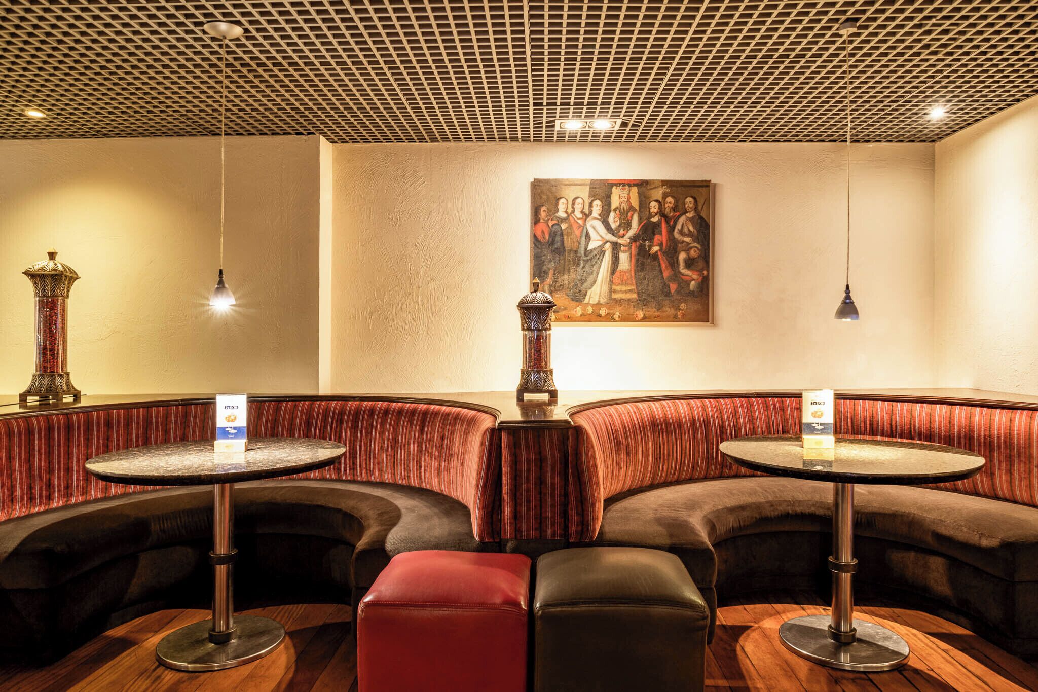 Un coin salon avec des banquettes rembourrées, une table ronde et une lampe décorative.