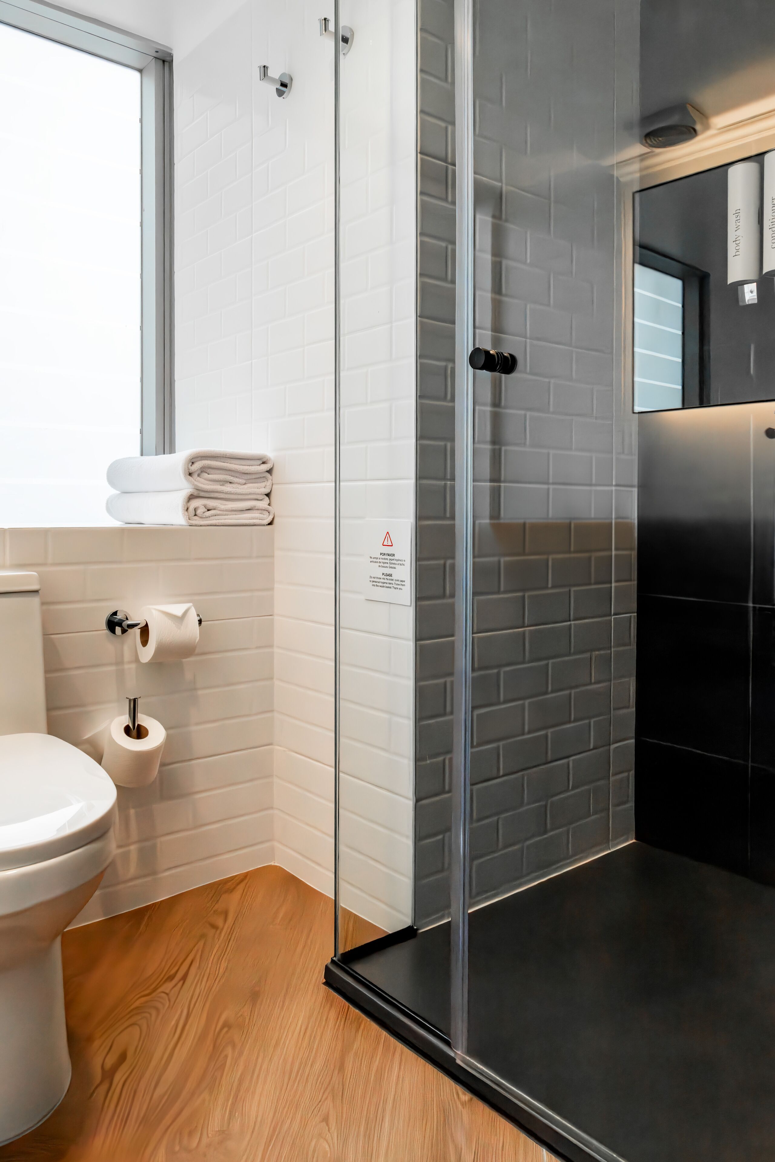 A modern bathroom with a glass shower enclosure, a toilet, and a sink with a towel rack.