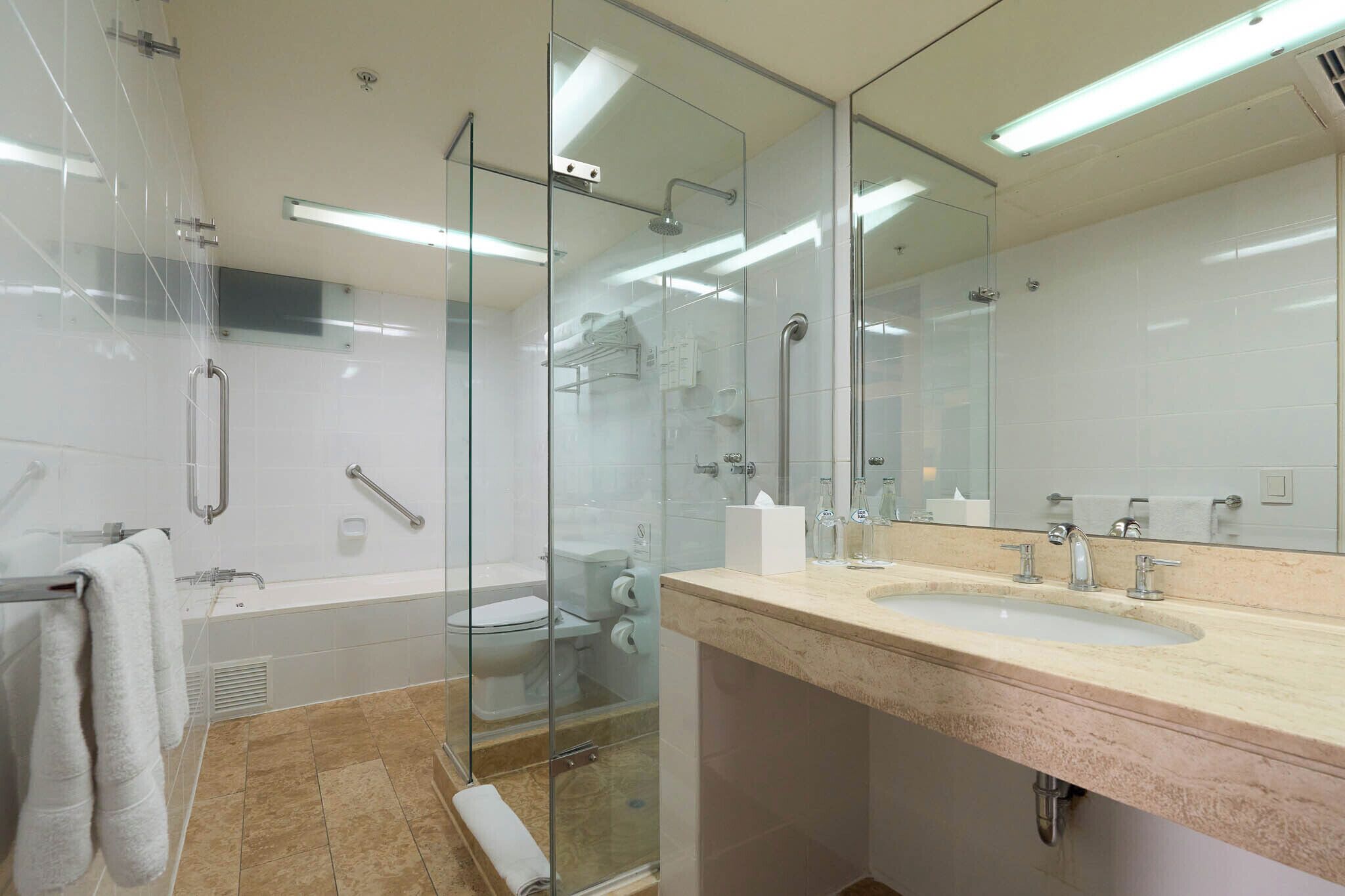 Un baño moderno con cabina de ducha de vidrio, bañera, lavabo con espejo y retrete.