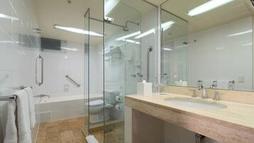 Un baño moderno con cabina de ducha de vidrio, bañera, lavabo con espejo y retrete.