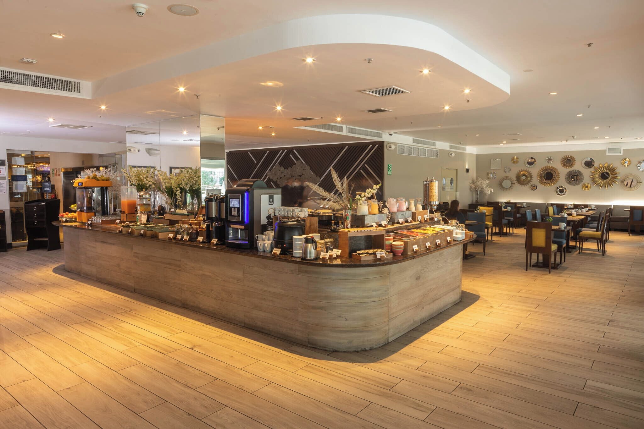 A modern cafe with a central counter, seating area, and decorative wall art.