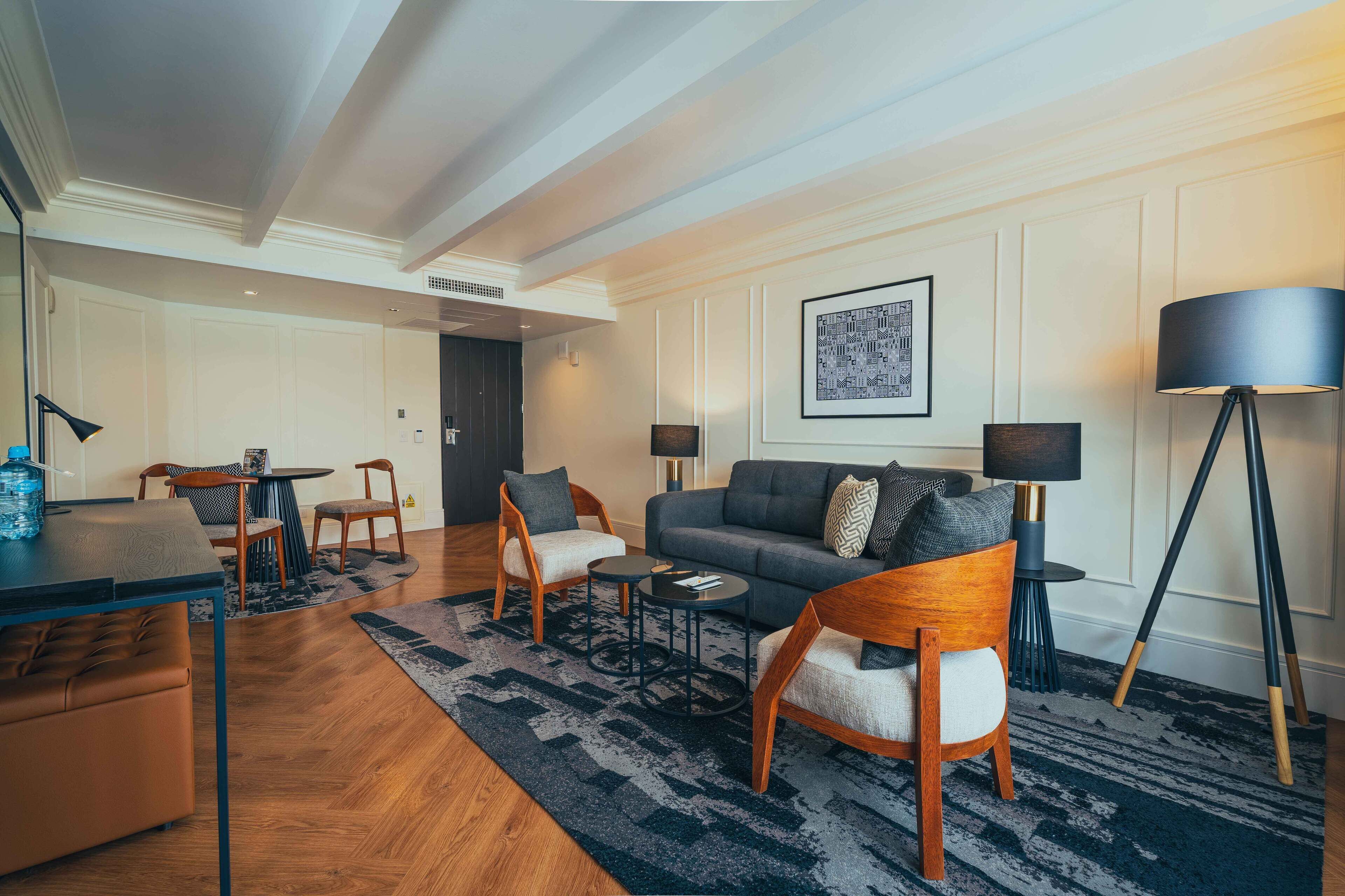 A modern living room with a sofa, armchairs, a coffee table, and a dining area with a table and chairs.