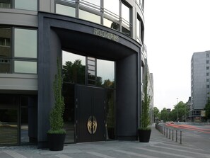 A modern building entrance with a large black archway and the name "ROOMERS" above it. - Roomers Frankfurt Central, Autograph Collection (Frankfurt)